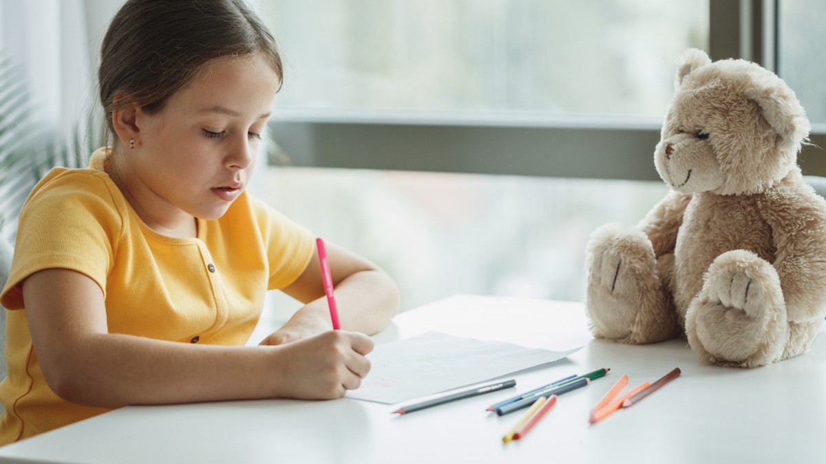A school-age child concentrating on English writing practice at a bright home desk