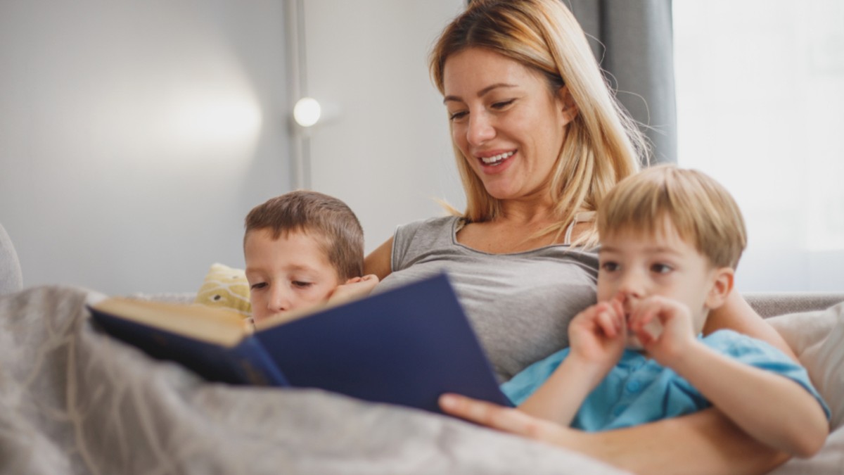 A parent reading an English picture book with two young children at home